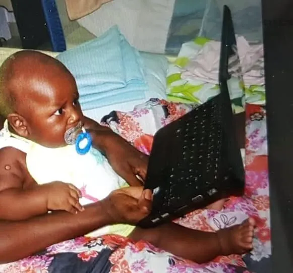Me at five months old, sitting next to an open laptop.